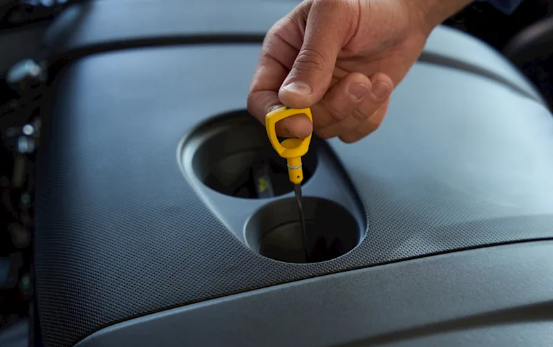 image of someone checking their oil levels with a dipstick