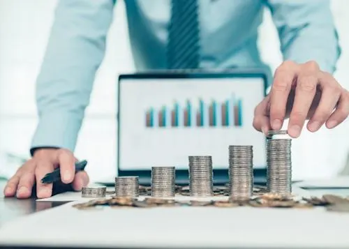 Person counting their money in front of an open laptop