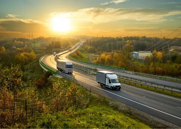 Two trucks driving with the sun behind them