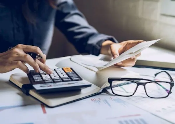 Person using a calculator and looking at paperwork