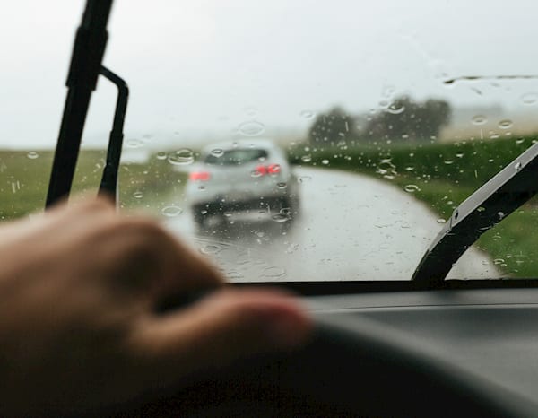 image of a driver, driving in the rain with a car in front