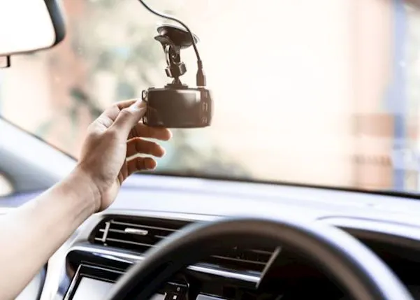 Person adjusting their dash cam in the windscreen