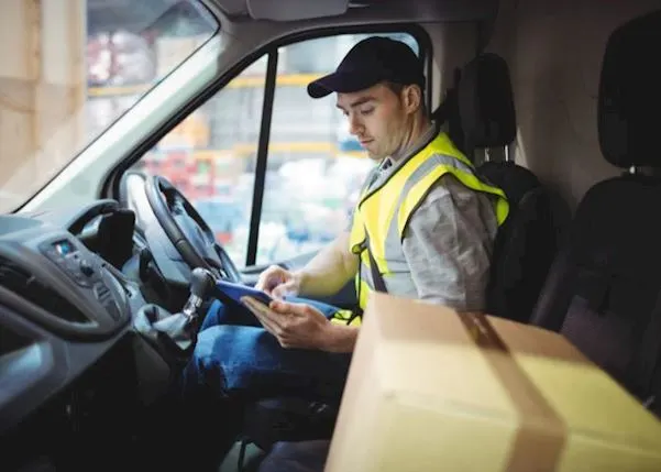 A delivery driver in a van on a tablet