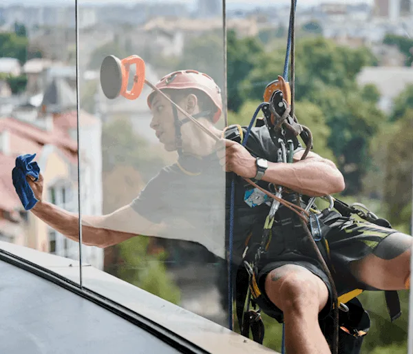 Cleaner harnessed up on the side of a building cleaning the windows