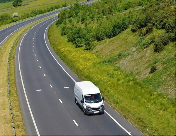 Commercial van driving on road with AI dash cam providing cloud, mobile, and desktop access to footage