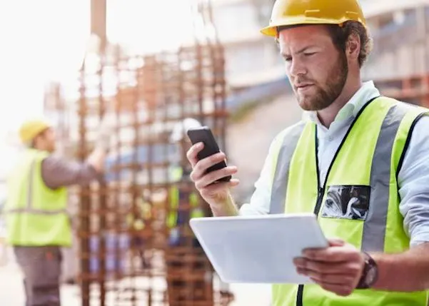 Construction worker looking at their phone on a worksite