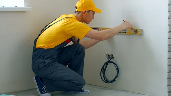 builder measuring a wall with a spirit level.