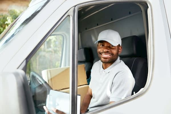 Image of a delivery driver smiling before delivering boxes. in a van being tracked with GPS vehicle tracking