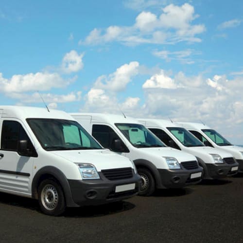 Image shows four white transit vans in a row
