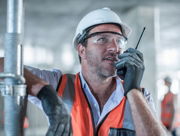 Foreman talking to a colleague on the walkie-talkie about the latest job in their work flow.
