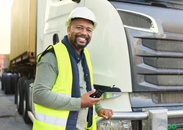 Truck driver stood in front of his vehicle holding a walkie talkie