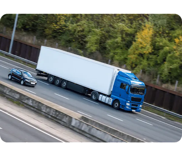 Black car is passing a blue lorry with a white trailer attached