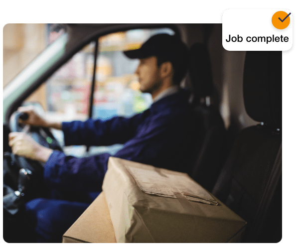 A delivery man has boxes next to him and in the top right of the image there is an orange circle with a tick inside and underneath it says "job complete"