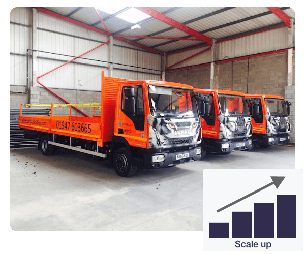 Three orange trucks are parked next to each other in a warehouse and in the bottom right there is a bar chart showing the scale up growth