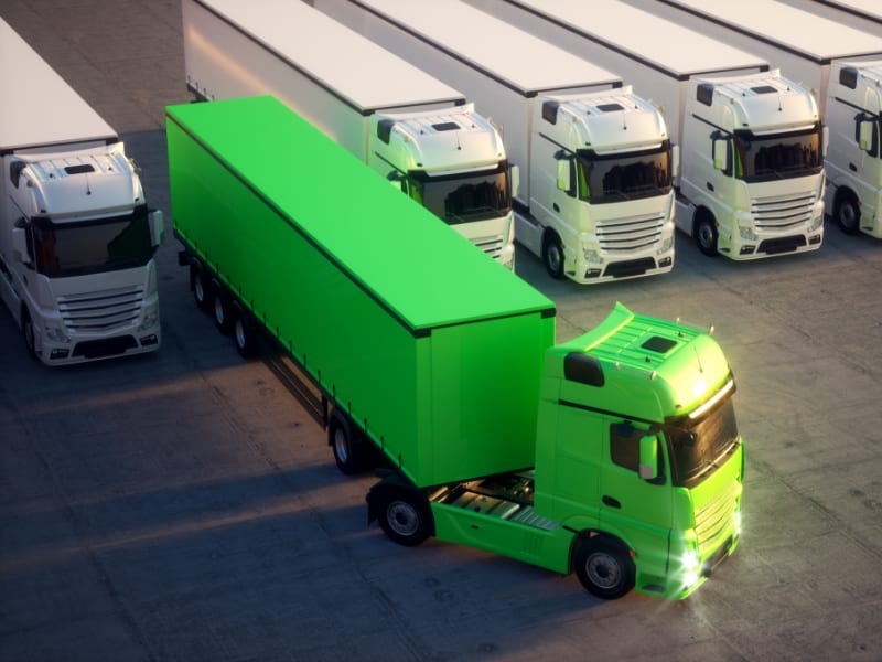 A fleet of white trucks but one truck is green as part of efficient fleet management