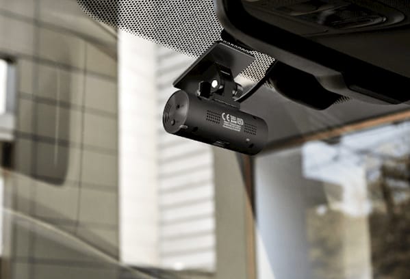 image of a dash cam placed neatly behind the rear view mirror on a front window screen of a vehicle