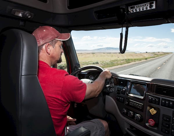 Man wearing a red polo shirt and red baseball cap driving a lorry