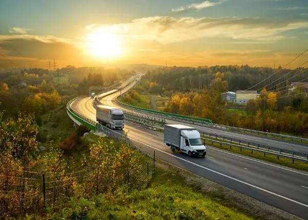 Trucks driving on a road at sunset