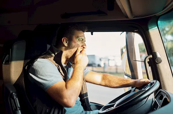 Driver yawning in his vehicle at the wheel.