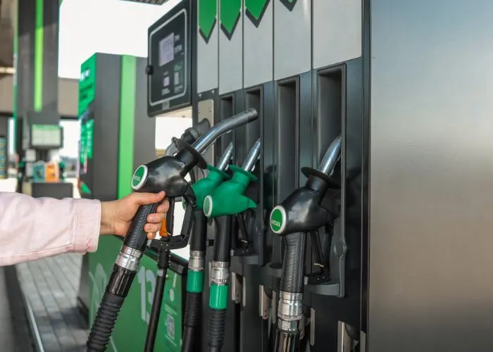 Image of person reaching for a fuel pump to fill up their car.