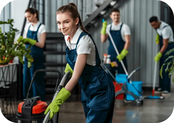 2 females and 2 males are cleaning up an office in blue overalls and white shirts
