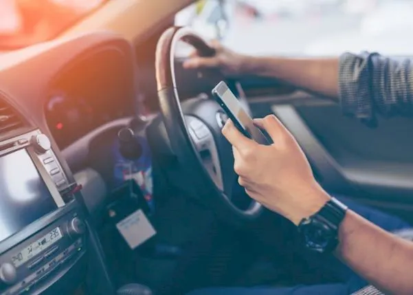 Driver in a vehicle with his phone in his hand
