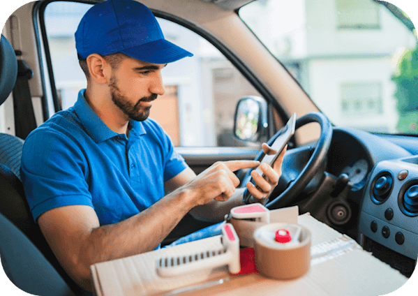 Delivery driver dressed in blue sat in his van on the mobile app