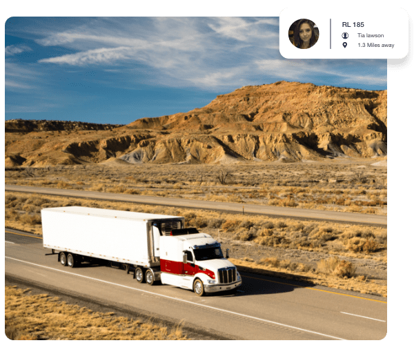 White and red lorry driving in desert land next to a mountain range.