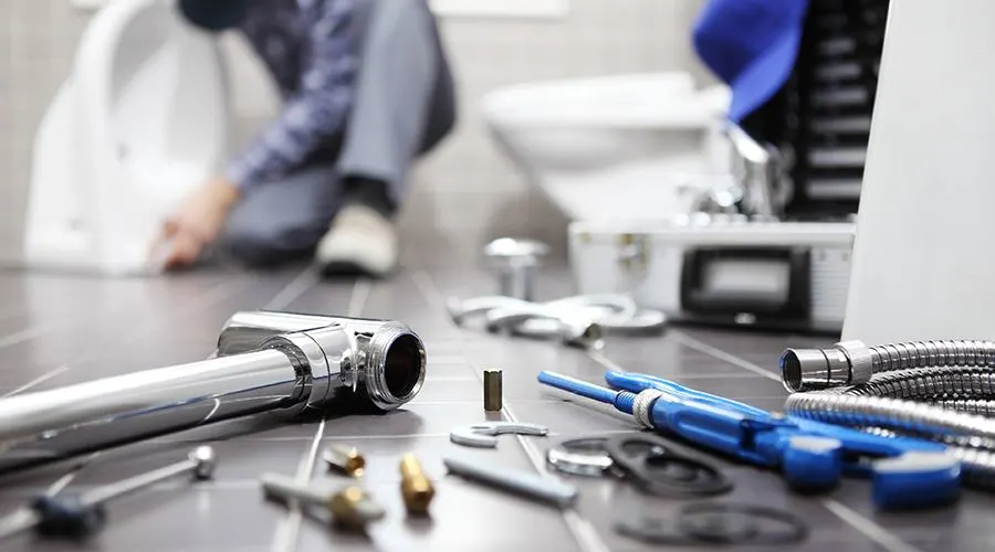 Plumber's tools laid out on the floor whilst he works