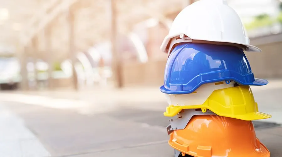 Orange, white, yellow and blue hard hats stacked up