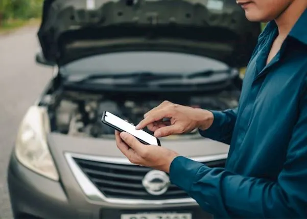 Car broken down on the road with a person using their phone in front of it